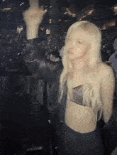 a woman in a crop top is standing in front of a crowd in a stadium .