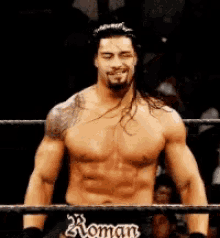 roman reigns without a shirt is standing in a wrestling ring
