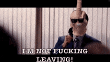 a man in a suit and tie is wearing a mask with a middle finger on it .