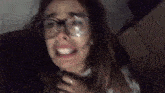 a woman wearing glasses is crying and making a funny face in a dark room .