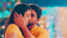 a man is kissing a woman on the forehead while wearing a yellow shirt