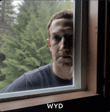a man looking out of a window with the word wyd written below him