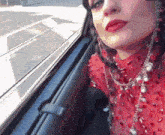 a woman in a red dress looks out a car window
