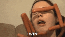 a woman is holding hot dogs in front of her face .