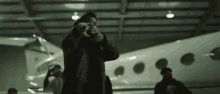 a man is standing in front of a plane in a hanger holding a gun .