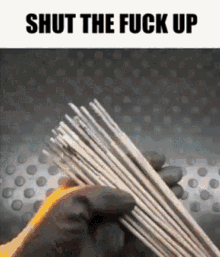 a person wearing gloves is holding a bunch of welding rods with the words shut the fuck up above them .