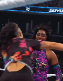 two women are hugging in front of a sign that says sm