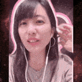 a woman wearing earbuds looks at the camera with a pink background
