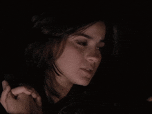 a close up of a woman 's face with her eyes closed in the dark .
