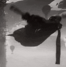 a black and white photo of a person flying through the air in a hammock .