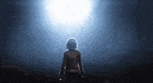 a woman stands in a dark room looking at the light