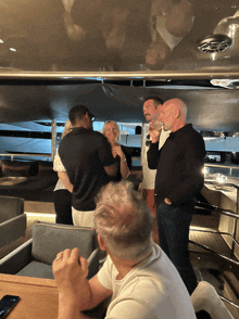 a group of people are standing around a table with a phone in front of them