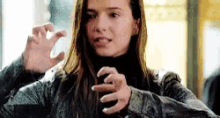 a woman in a black turtleneck and a leather jacket is making a claw gesture with her hands .