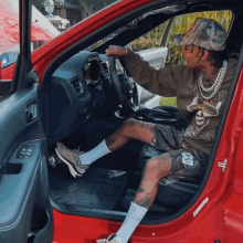 a man is sitting in a red car wearing a sweatshirt that says swag on it