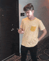 a young man in a yellow and white striped shirt stands in front of a door with the number 833 on the wall