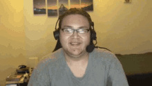 a man wearing glasses and headphones is smiling while sitting in a room .