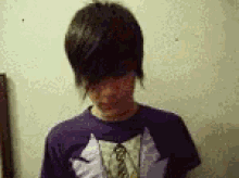 a boy with short hair is wearing a purple shirt with a wolf on it .