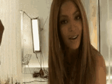 a woman with long blonde hair is standing in front of a mirror .