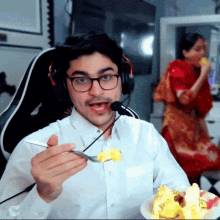 a man wearing glasses and headphones is eating a piece of food with a fork