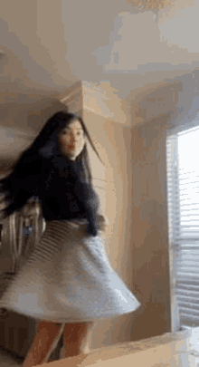 a woman in a striped skirt is dancing on a table in a living room .