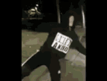 a person in a black hoodie is walking down the street at night .