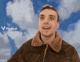 a man in a brown jacket stands in front of a cloudy sky with the words " viggle.ai " on the bottom