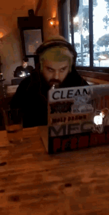 a man with green hair is sitting at a table with a box that says " clean " on it