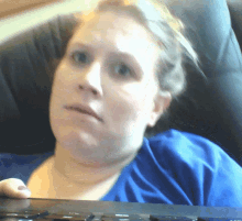 a woman in a blue shirt sits in a chair holding a keyboard