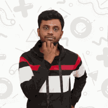 a man with his hand on his chin stands in front of geometric shapes