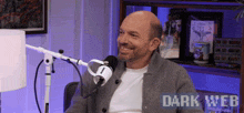 a man sitting in front of a microphone with the words dark web on the bottom right