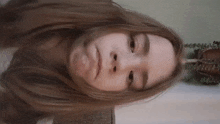 a young girl with long hair is making a funny face while looking at the camera .