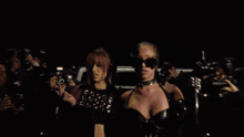two women standing next to each other wearing sunglasses