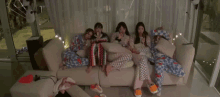 a group of girls are sitting on a couch eating ice cream