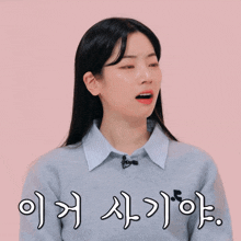 a woman wearing a sweater and a striped shirt has a microphone on her neck and a pink background with chinese writing on it