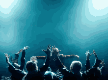 a crowd of people raising their hands in the air
