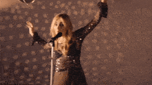 a woman is singing into a microphone with her hair in the air
