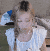 a woman wearing headphones and a braided ponytail looks down at something