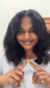 a woman is smiling and making a heart with her fingers