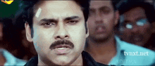 a man with a mustache has a bandage on his forehead and the website tvnxt.net is in the corner
