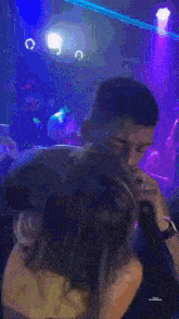a man is singing into a microphone while another man watches