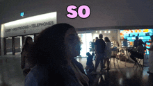 a woman stands in front of a building that says lobby restrooms telephones