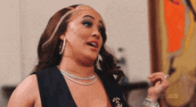 a woman wearing a necklace and hoop earrings is making a face