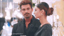 a man in a suit and a woman in a black dress looking at each other