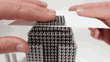 a person is holding a piece of paper with a bunch of balls on it