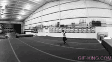 a black and white photo of a person doing a trick in a gym with a sign that says cheer force fund