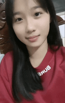 a girl wearing a red shirt with the word bnkb on the collar