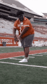 a man in a texas shirt is standing on a football field .