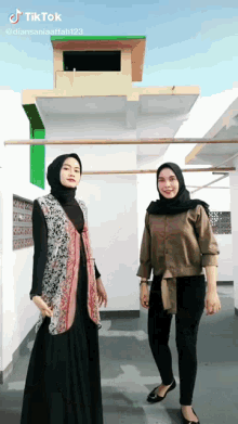 two women are standing next to each other in front of a building with tik tok written on the bottom