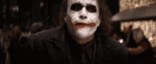 a close up of a man wearing a joker mask in a dark room .