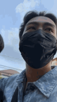 a man wearing a mask and a denim shirt